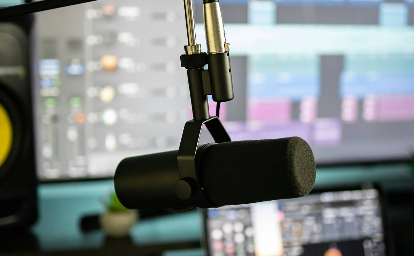 A broadcast microphone on a boom arm in front of a screen