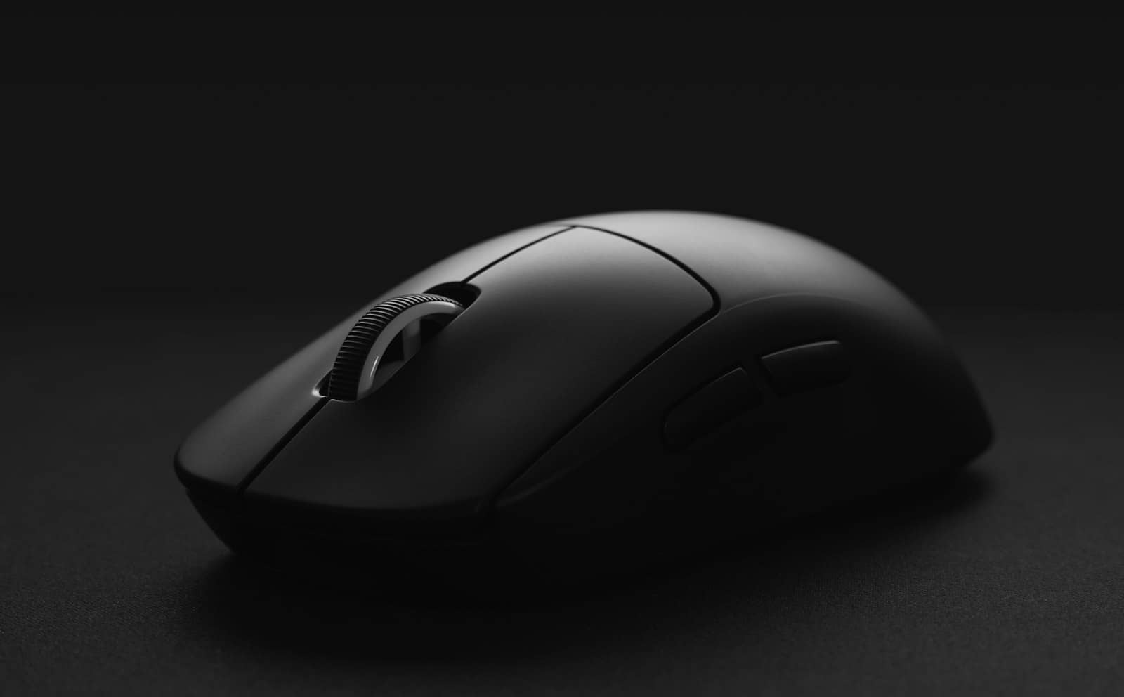 A black wireless gaming mouse on a dark surface