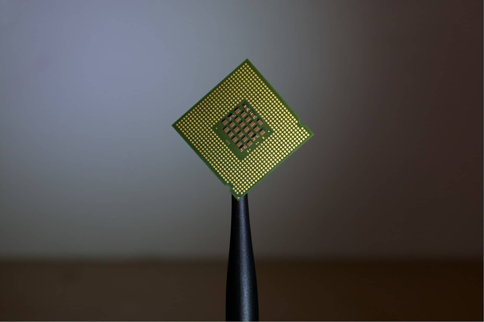 A computer processor CPU chip held up against a dark background