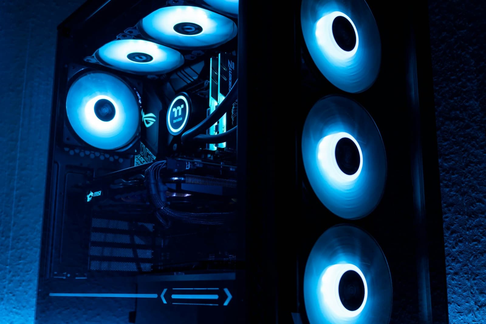 A blue-lit desktop PC tower with visible cooling fans