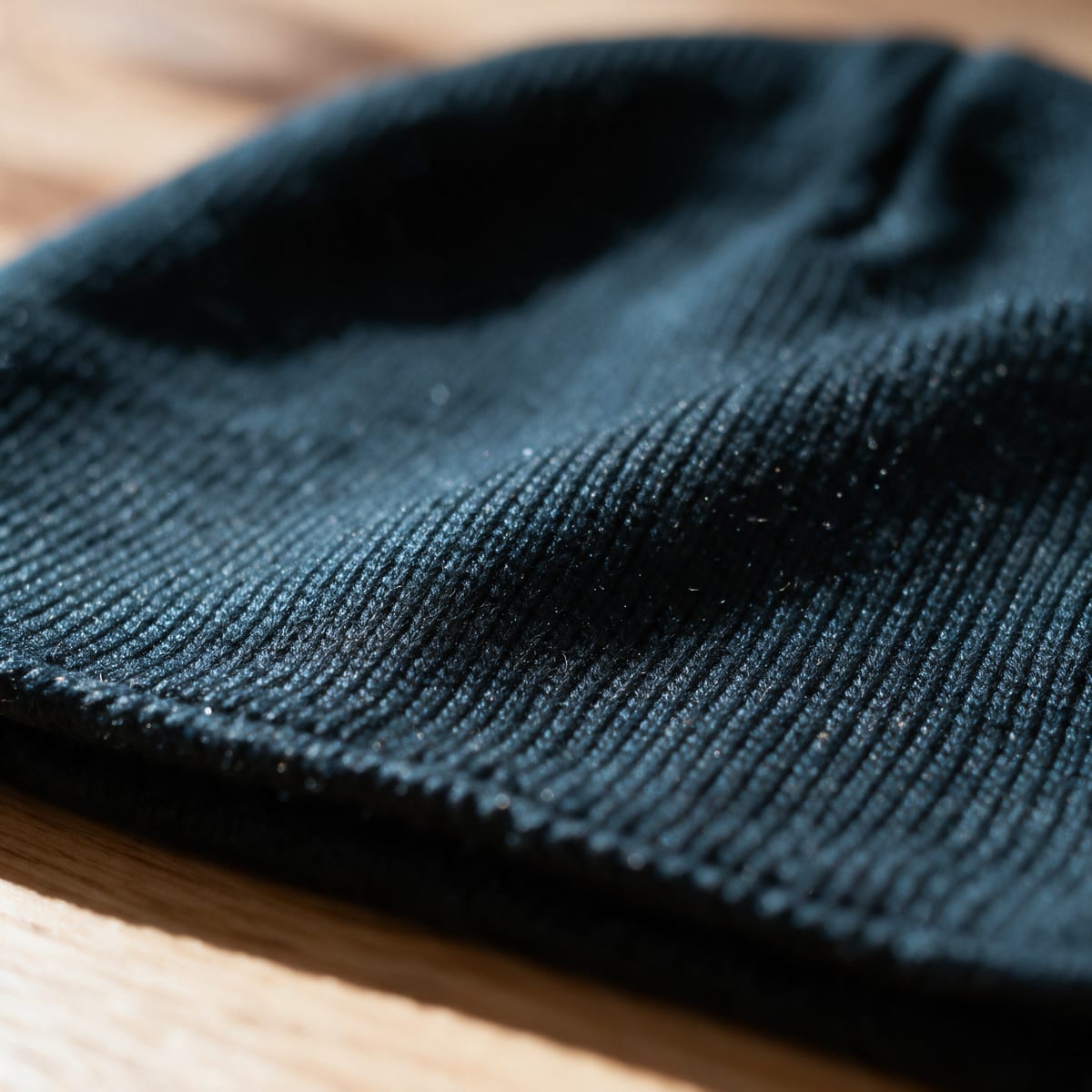AI close-up of dark knit fabric with visible ribbed texture on a wooden surface