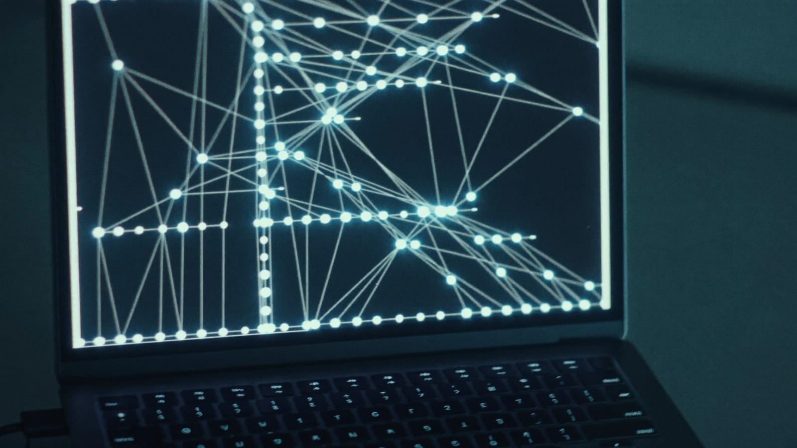 A laptop on a moody desk showing an abstract node-graph agent workflow