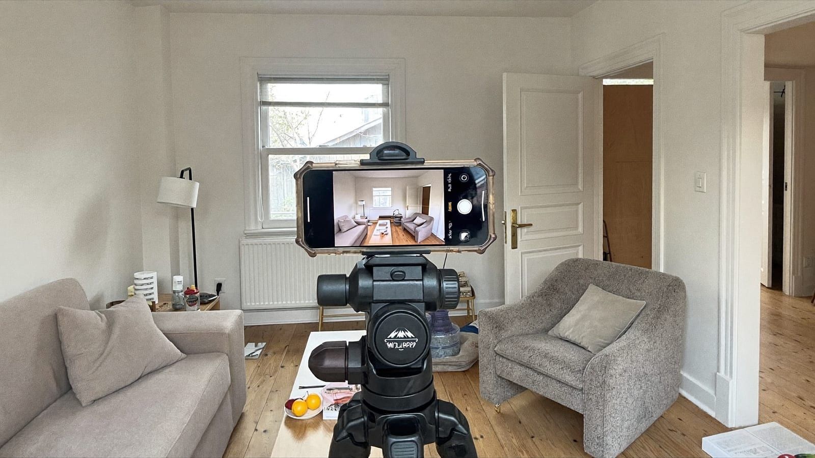 A smartphone on a small tripod filming a clean, freshly finished room