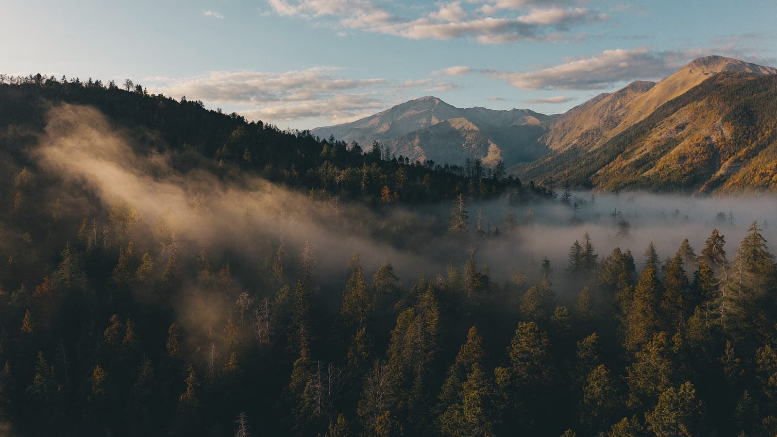 Cinematic aerial drone shot of a mountain landscape at golden hour representing an establishing shot from AI video generation