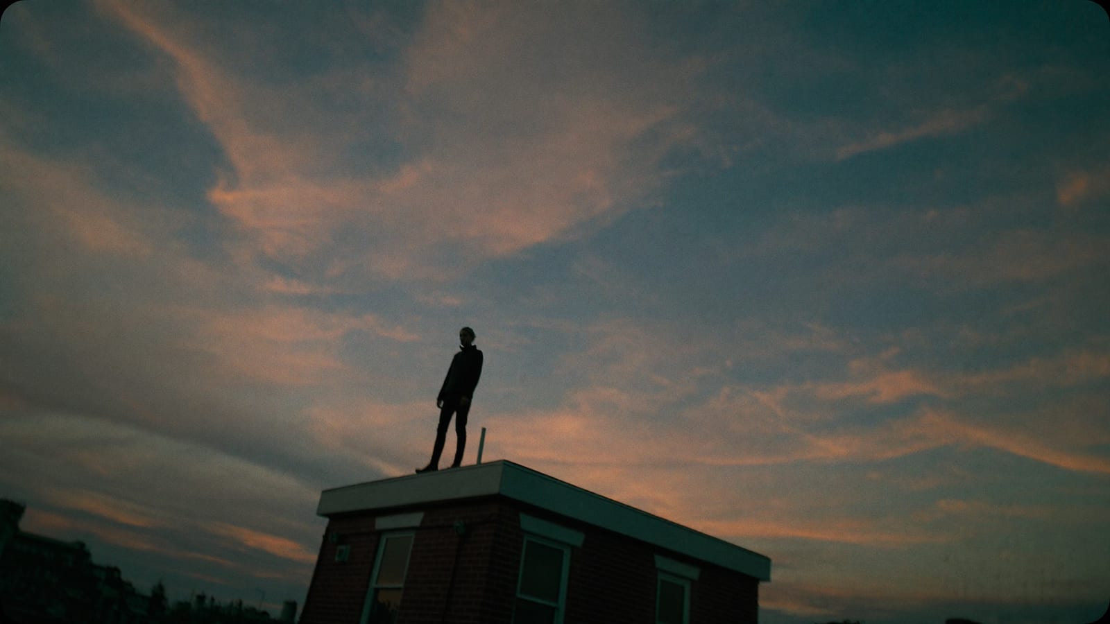 A low-angle cinematic rooftop shot at dusk, a still from a Higgsfield generation