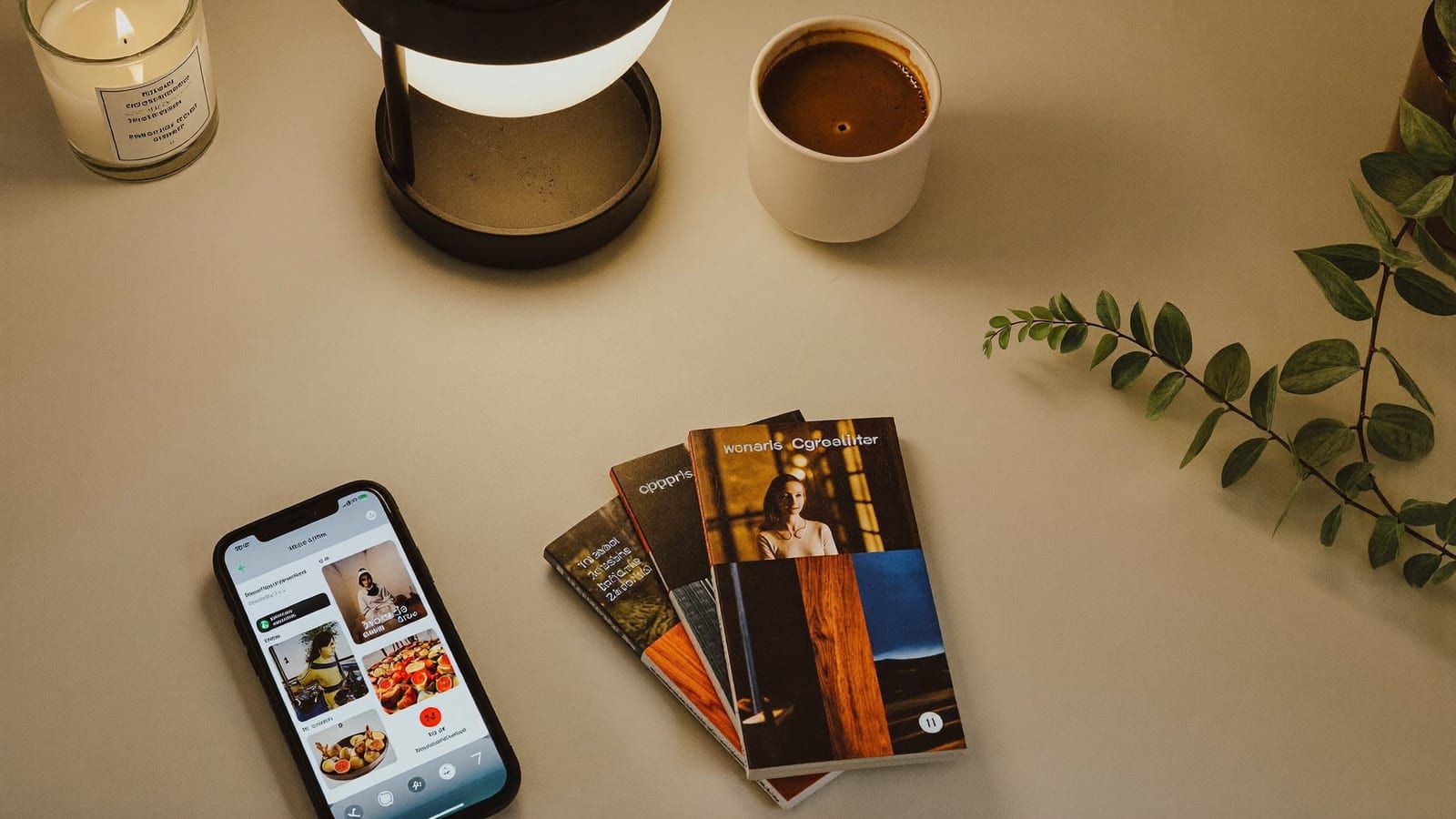 A top-down flat lay of a phone, a ring light, a candle and a plant — a faceless creator's corner