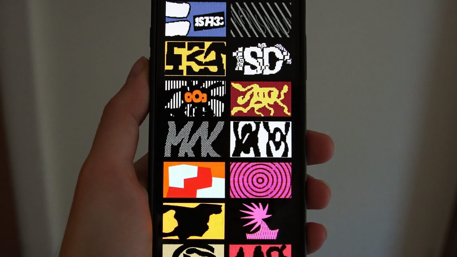 A phone held in hand showing a vertical feed of small video thumbnails