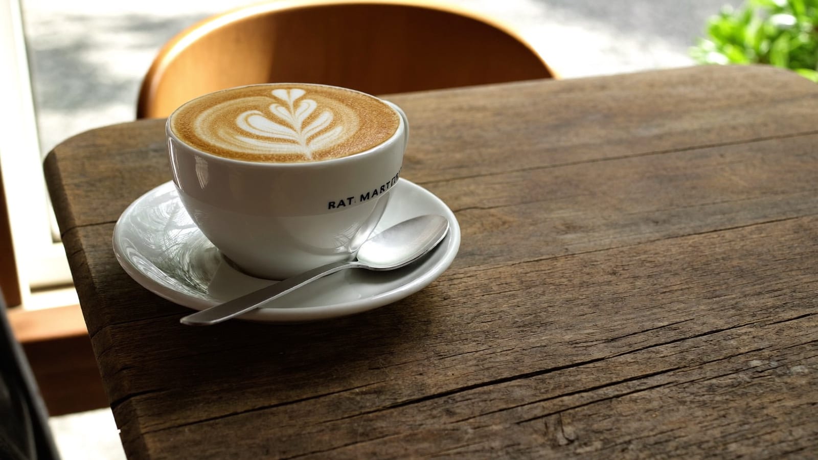 A latte with leaf latte-art on a rustic wooden table, appetising food photography