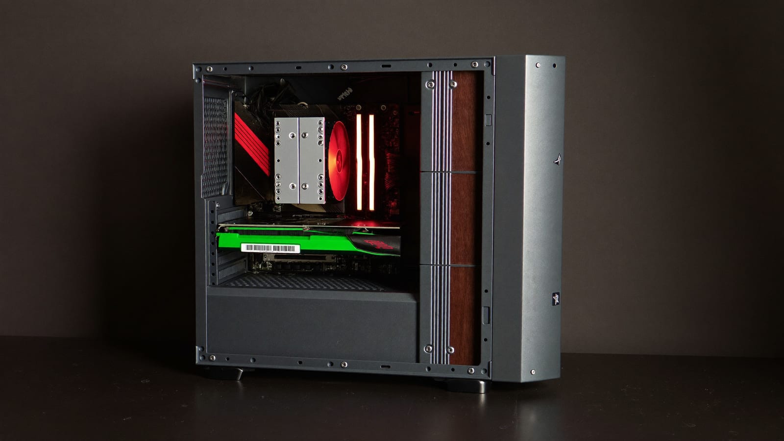 A desktop PC with an open case and a glowing graphics card on a dark desk