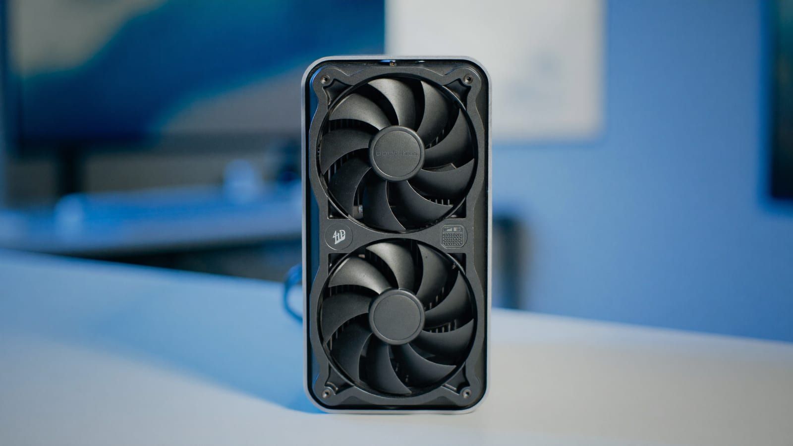 A compact dual-fan graphics card on a desk beside a keyboard