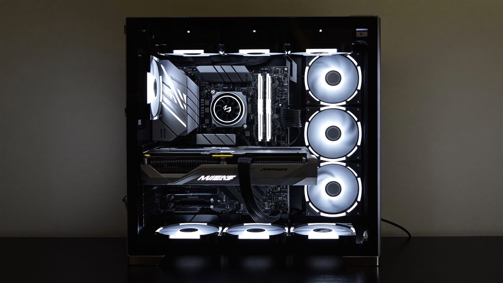A glowing open-air PC build on a test bench in a dim room with soft RGB lighting