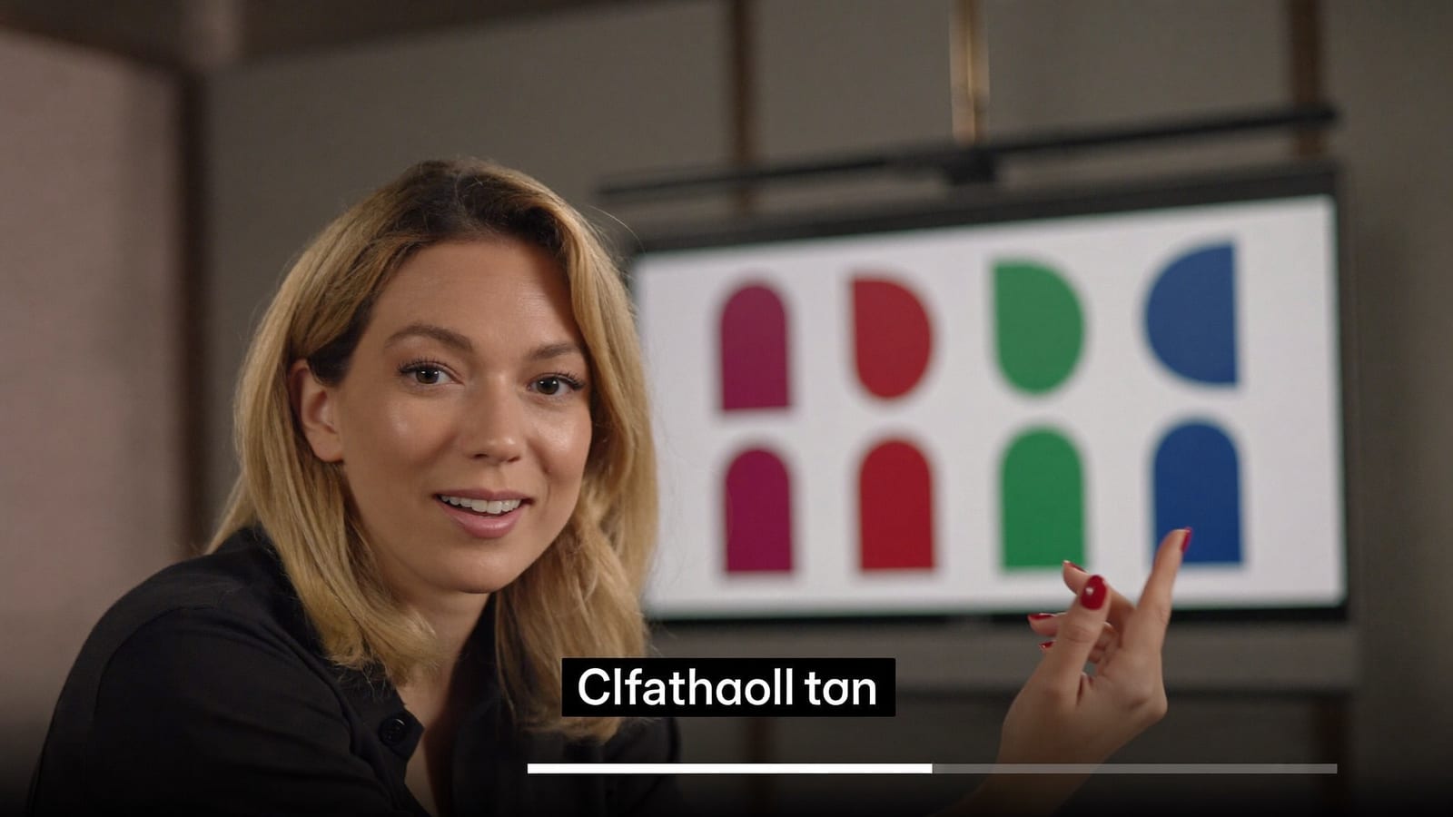 A friendly presenter framed like a talking-head lecture video on a softly lit set, gesturing to an unseen slide