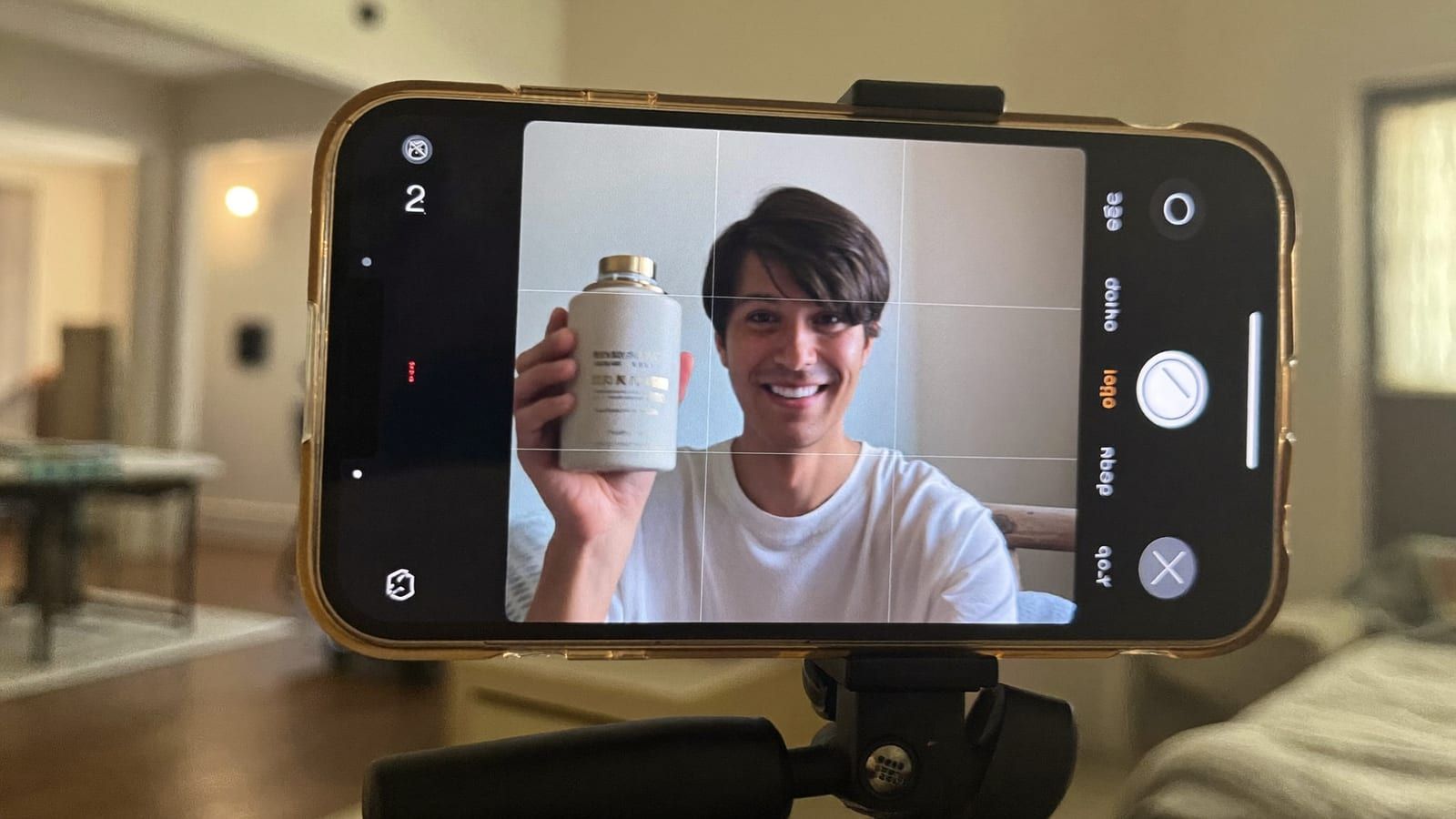 A phone on a tripod filming a person holding a plain product in a bright living room, UGC-style