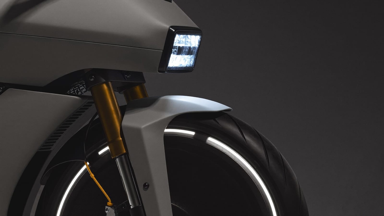Close detail of an original futuristic motorcycle's front end and headlight in dramatic dark studio light