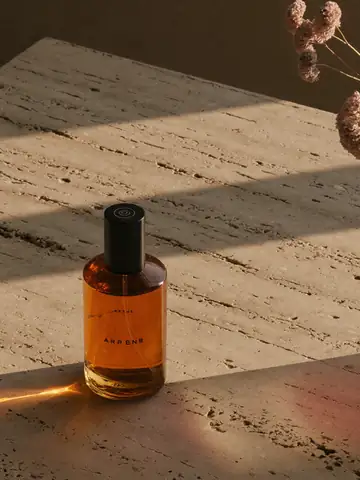 Product photo of an amber perfume bottle on stone