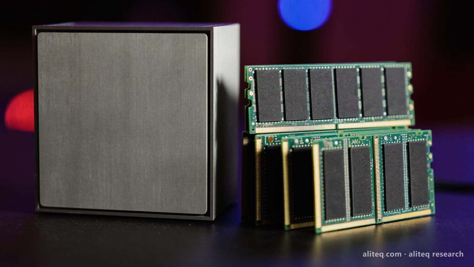 Photo illustration of a compact square aluminum desktop computer beside a stack of bare green memory modules on a dark desk
